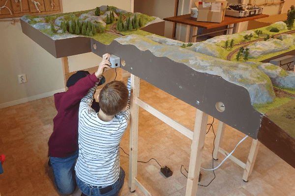 Två barn hjälper varandra med att sätta upp kontrollsystemet för en modulbana